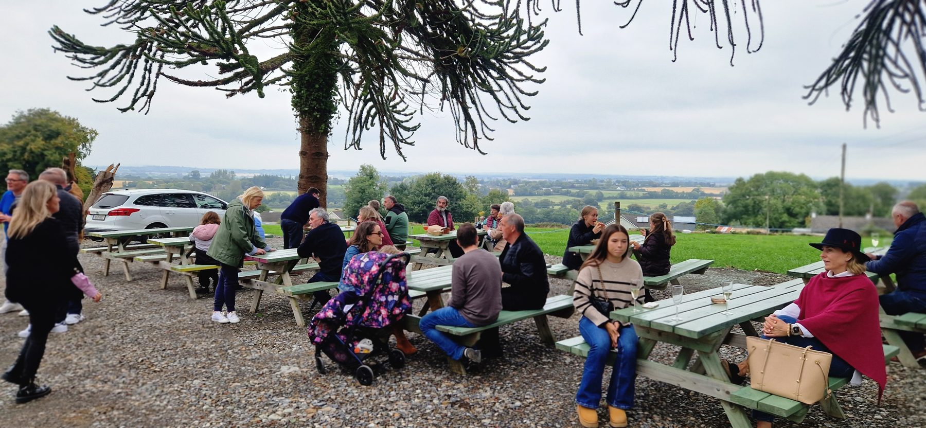 Guests at long picnic tables outside The View Café looking over the Carlow Valley
